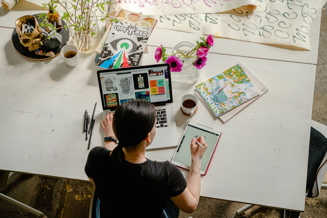 A person working on their online business using a tablet and laptop