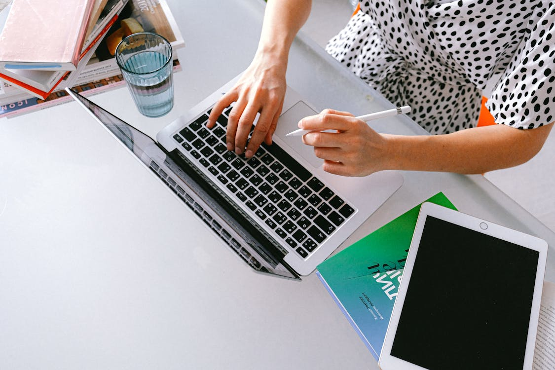 Top shot of a person using a laptop and holding a pen