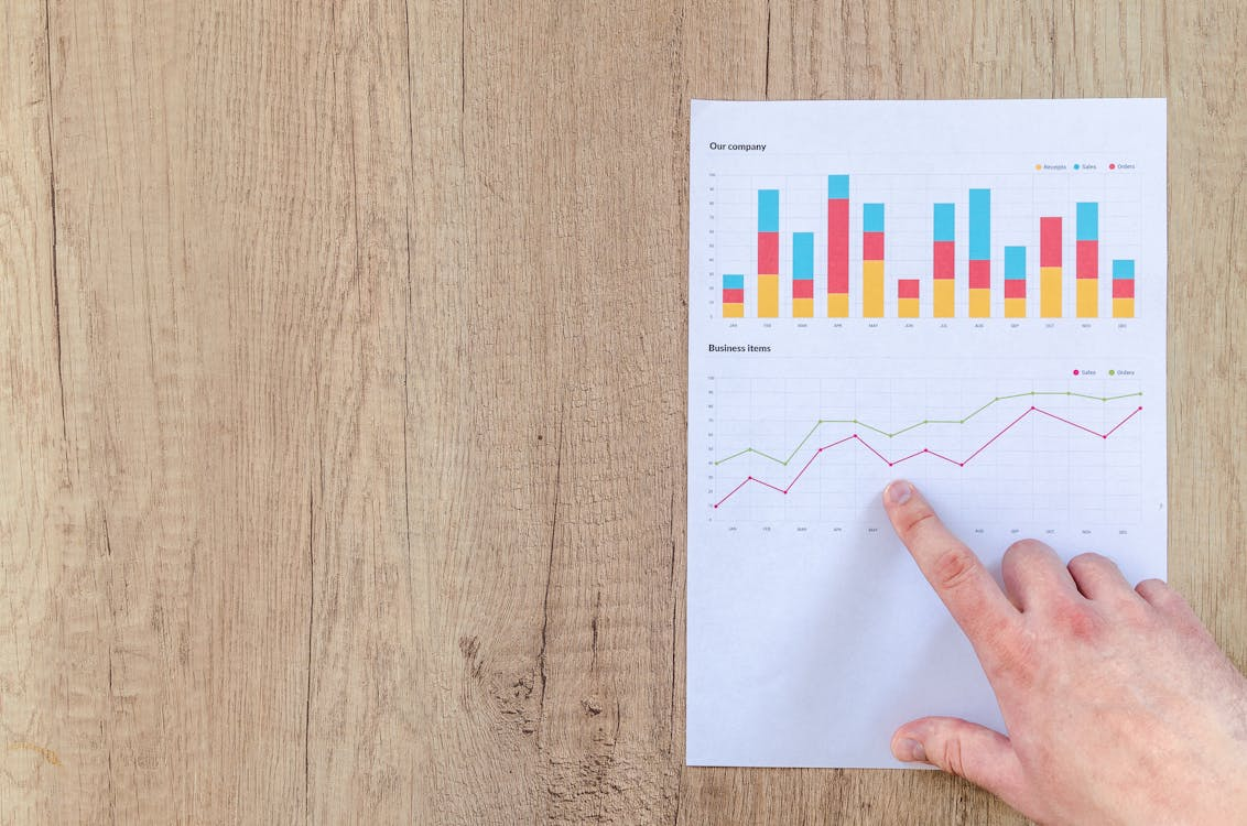 A person pointing to the graphs on a paper