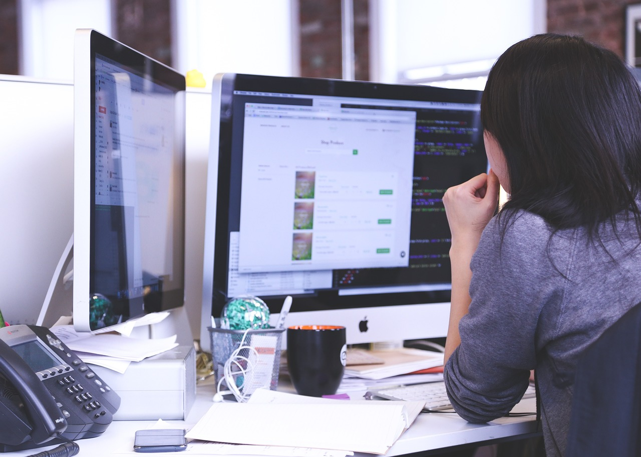 A person looking at a desktop with a mug and papers on their desktop