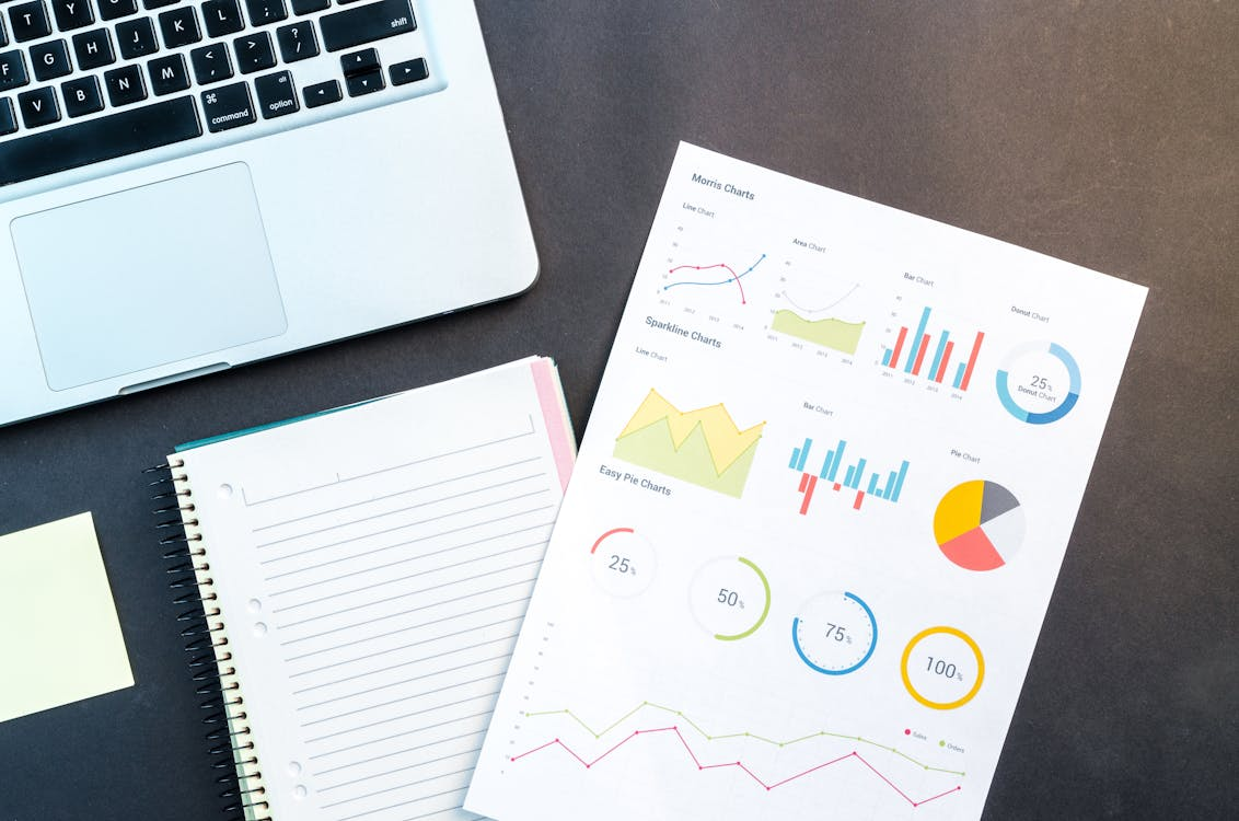 A document with graphs next to a laptop and notebook