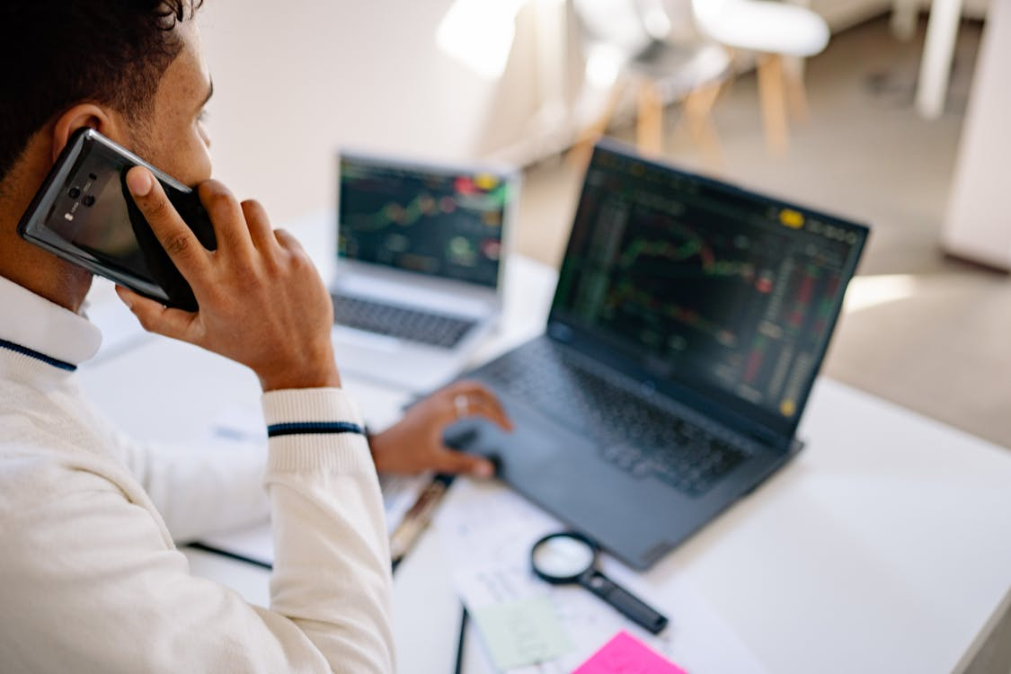 an individual on a call while navigating financial statistics on their laptop