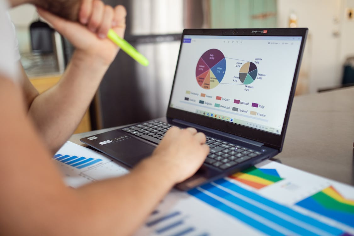 an individual navigating financial graphs on their laptop
