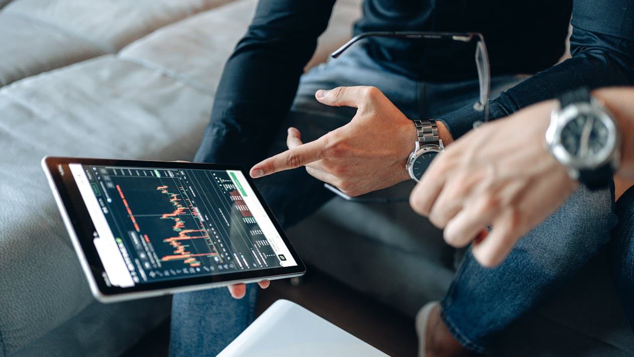 an individual pointing towards financial data on their tablet