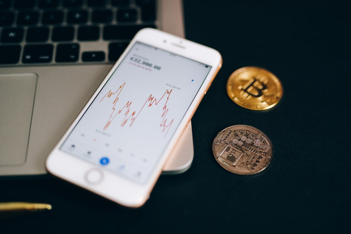 an iPhone placed on a laptop next to gold and silver coins